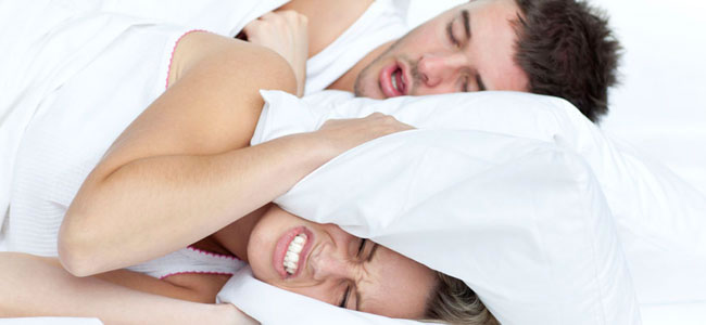 Una pareja en la cama intenta ver cómo dejar de roncar